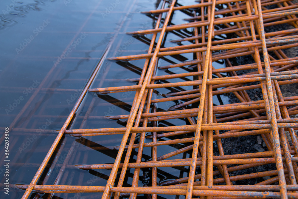 The rusty steel grid in pattern,Rusty construction metal mesh. Rusty Metal armature net for  road infrastructure  metal rebar for construction,Sites Soak in Water and Rust.