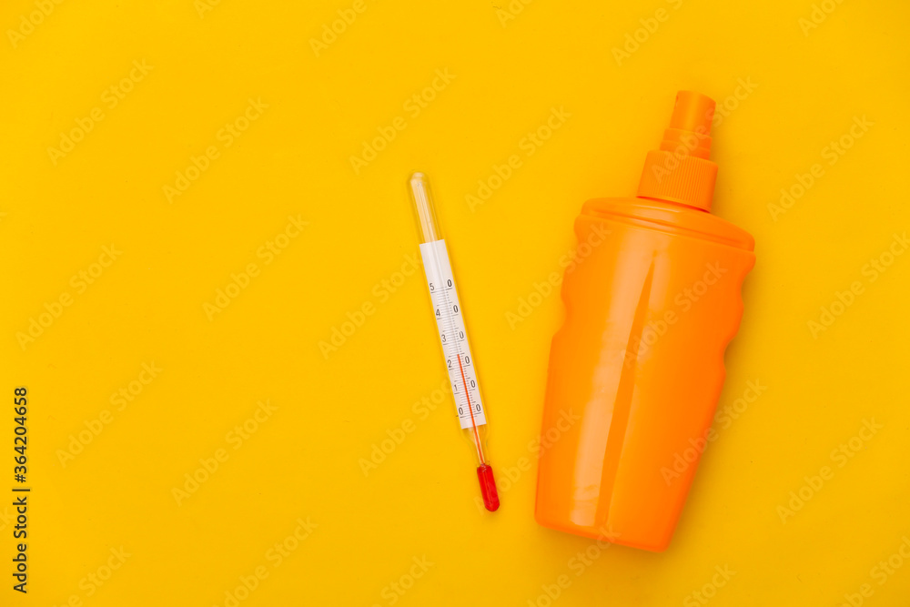 Beach vacation. Sunblock bottle and thermometer on a yellow background. Summer heat. Top view. Flat lay Beach vacation. Sunblock bottle and thermometer on a yellow background. Summer heat. Top view. Flat lay