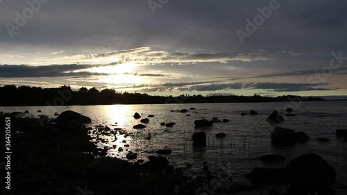 A beautiful sunset on the shore of a calm lake with some clouds.
