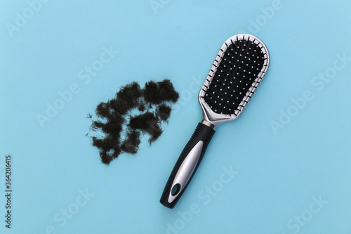 Hair brush with cut hair on a blue background. Top view