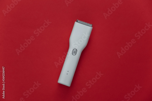 Wireless hair clipper on red background. Top view