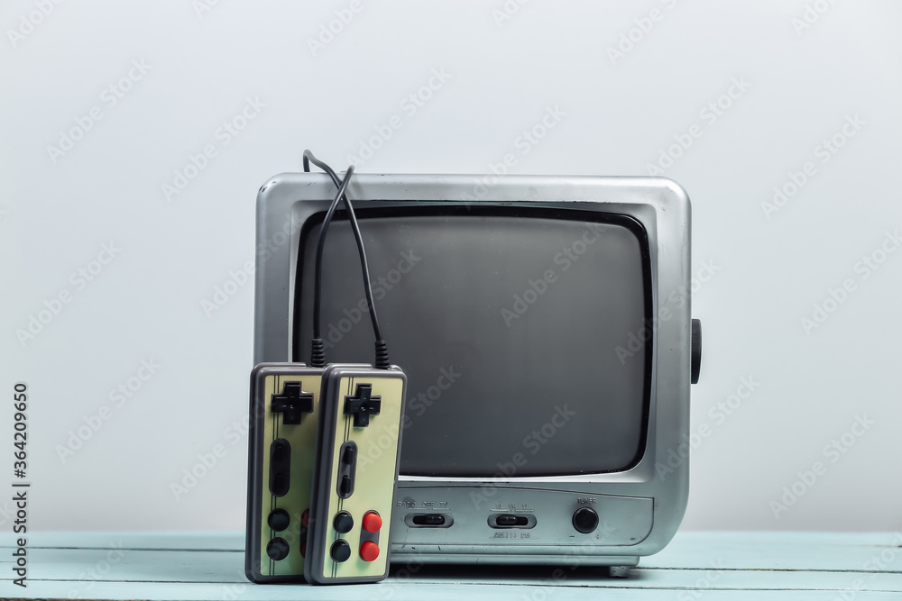 Old tv receiver with retro joysticks on a white wall background. Retro gaming. 80s