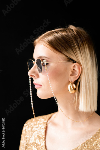 Young blond glamorous woman in sunglasses  glittering dress and golden earrings