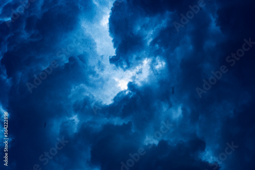 Dark background with ominous thunderclouds and rain pouring from the sky. Small raindrops when looking up.