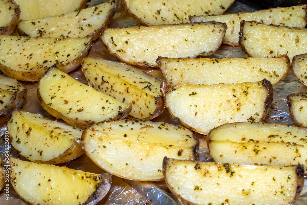 Background with slices of fried potatoes in oil and with greens on a metal baking sheet Background with slices of fried potatoes in oil and with greens on a metal baking sheet