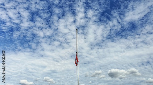 The national flag was dropped in half. The background is bright, with beautiful streaks and clouds.