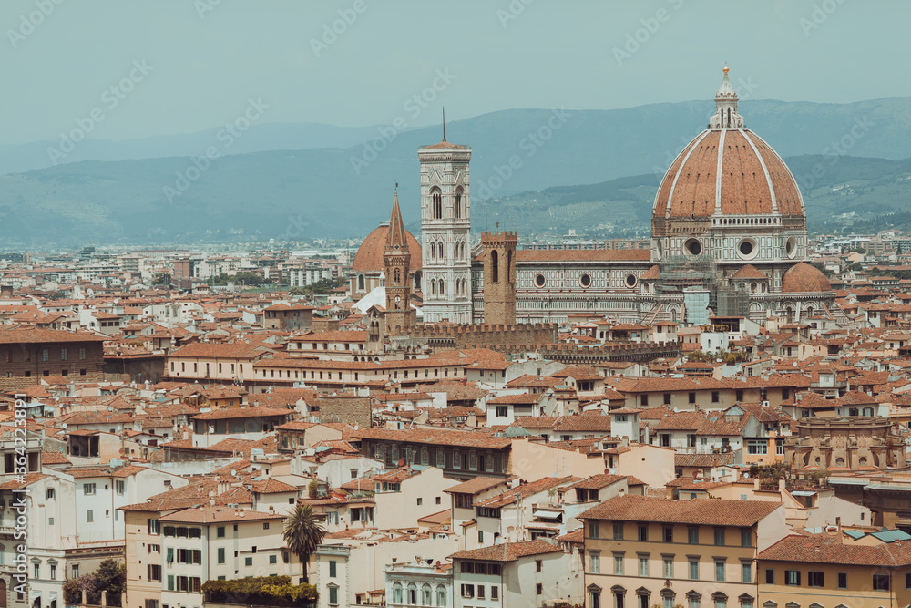 top aerial panoramic view of Florence city with cathedral, buildings houses with orange red tiled roofs and hills range, blue sky white clouds, Tuscany, Italy