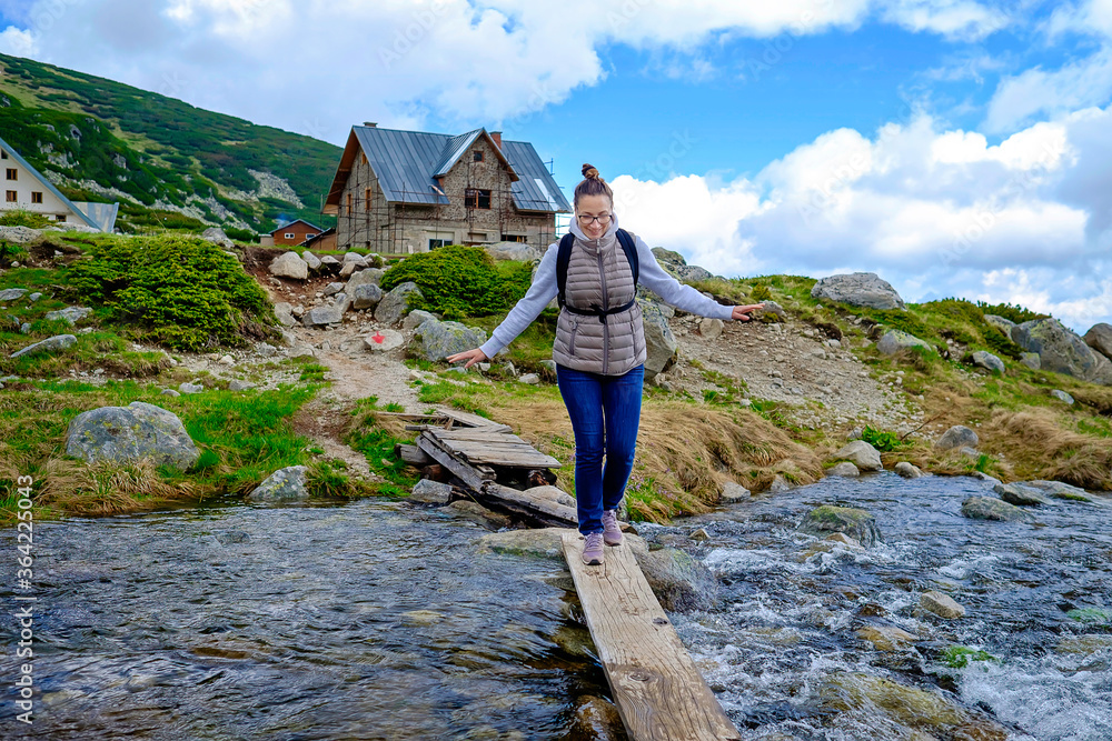 Naklejka premium Woman Walks Over Mountain River