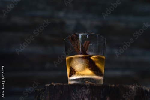 Still life of glass with whisky and cinnamon sticks