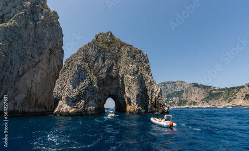 Panorama of Capri with the beautiful Faraglioni and boasts passing trought the famous arch, South of Italy.