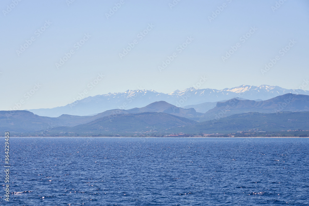 Foggy sea coast of Kolymbari, Crete, Greece with mountains and clear blue sky on a background.