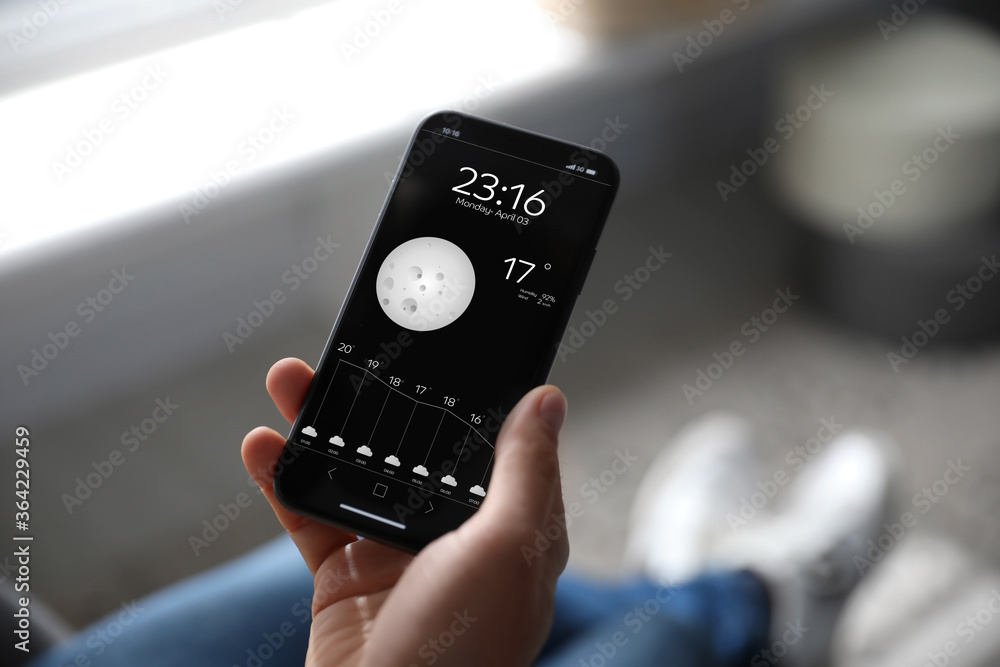 Man using weather forecast app on smartphone indoors, closeup Man using weather forecast app on smartphone indoors, closeup