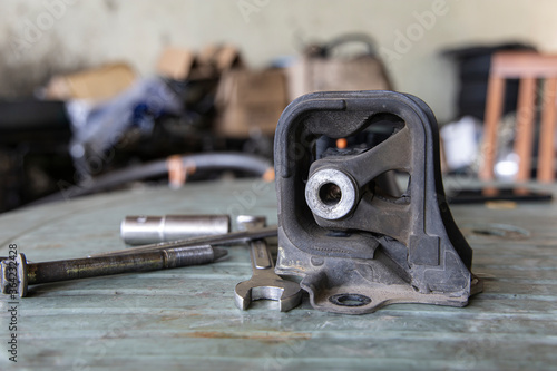 Old rubber engine mount with tools on the table background.