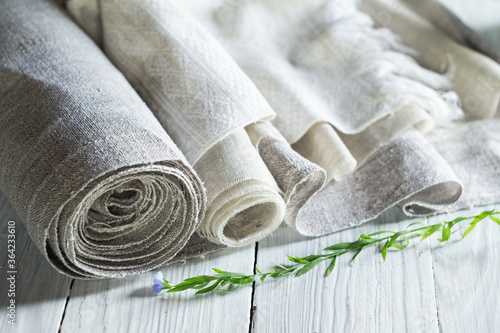 фотографія Old homespun and modern factory linen fabrics in rolls and blooming flax