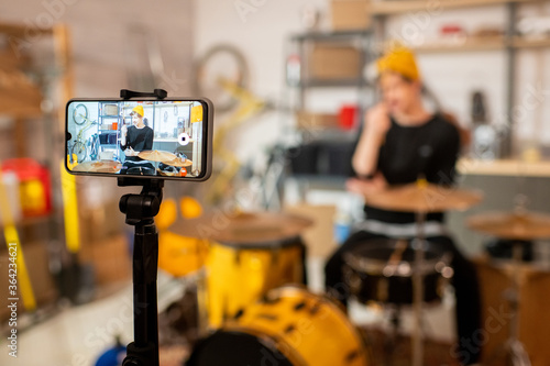 Young contemporary musician in front of drumset on smartphone screen