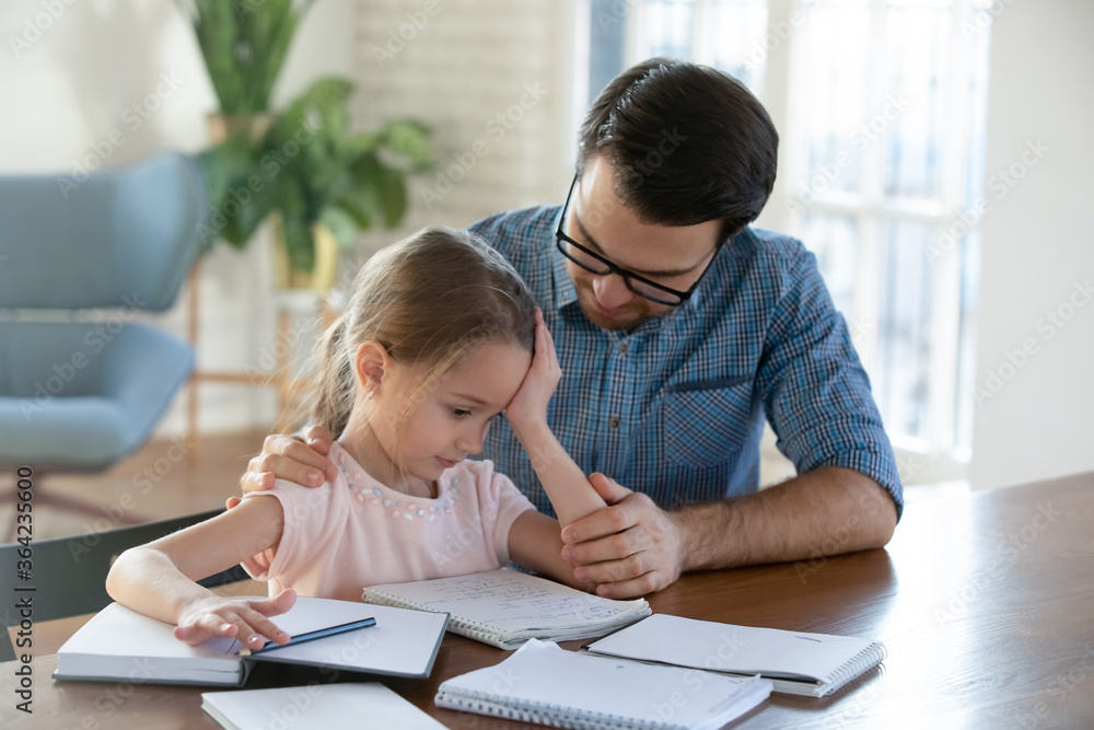 Caring father helping upset little daughter with school homework, sad pretty girl having problem with assignments, sitting at work desk with dad, studying together at home, homeschooling Caring father helping upset little daughter with school homework, sad pretty girl having problem with assignments, sitting at work desk with dad, studying together at home, homeschooling