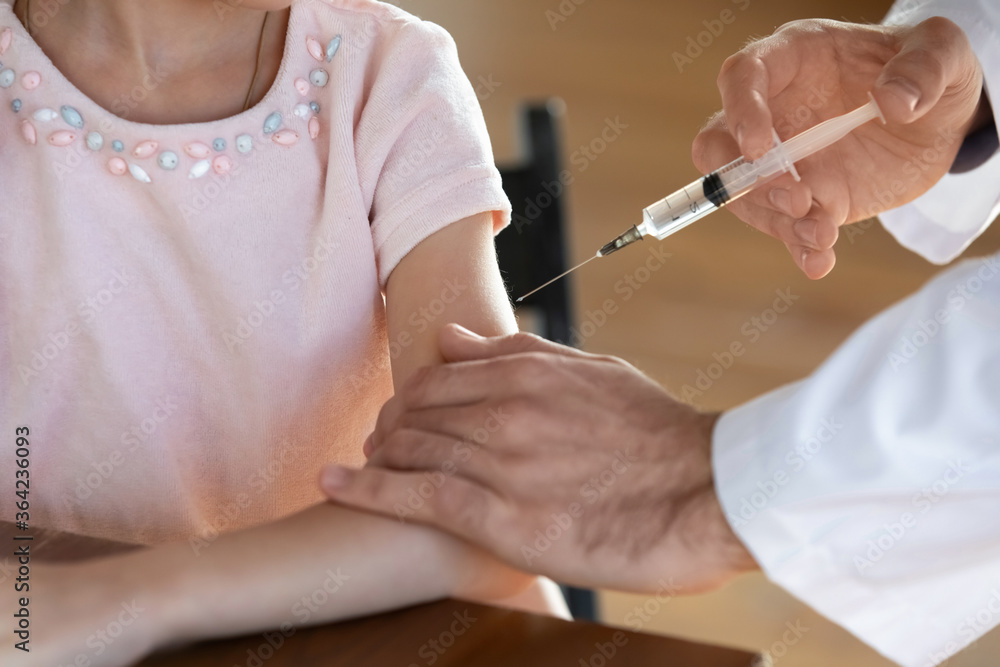 Close up doctor vaccinating little girl, holding syringe, therapist pediatrician vaccination making prick, injection to small patient, disease prevention, children healthcare concept Close up doctor vaccinating little girl, holding syringe, therapist pediatrician vaccination making prick, injection to small patient, disease prevention, children healthcare concept
