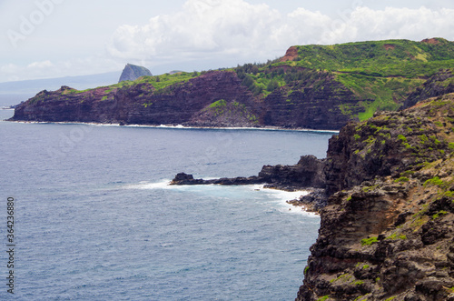 Panoramic view of rocky coastal line and shore of Kapalua Coast on Northern Maui peninsula with lush vegetation and sharp lava rocks and massive hills and mountains photo