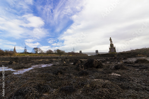 Coastal view from the high-tide seabed of the Menai Strait with the Nelson Statue, Britannia Bridge & St. Mary's Church in the distance, Isle of Anglesey, North Wales photo