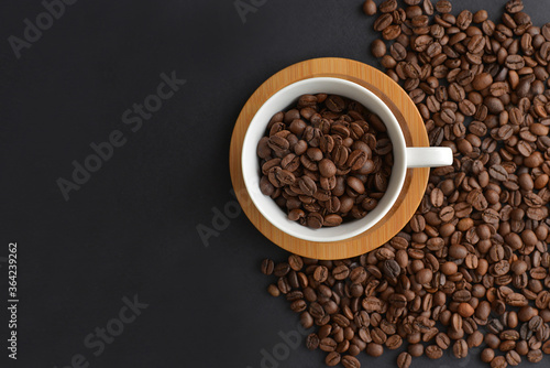Cup of coffee with beans on black background. Top view with space for your text.