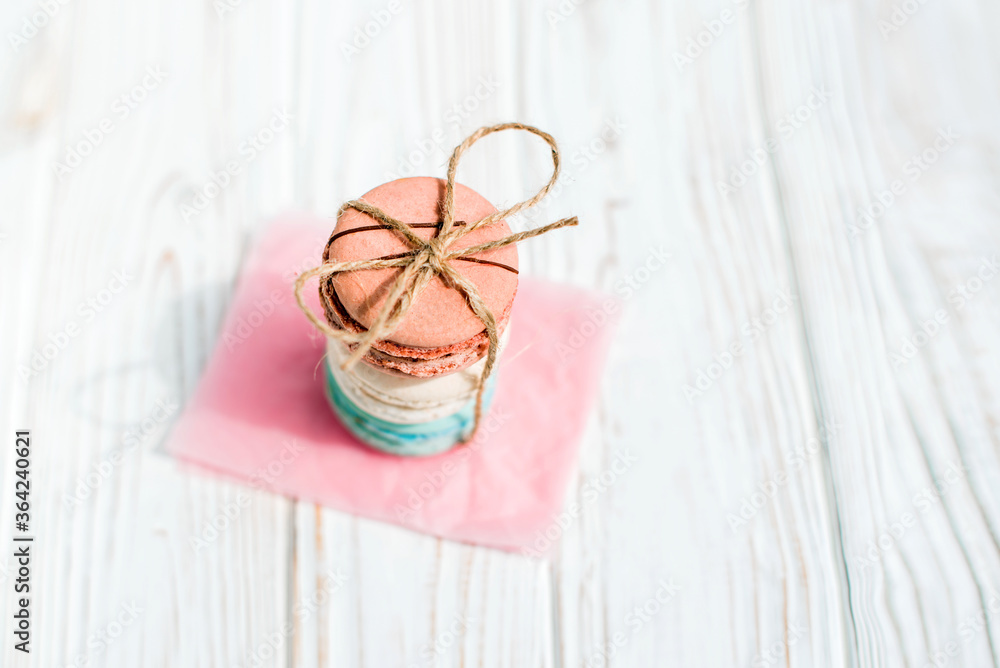 Top view of French macaroons tied with craft thread isolated on a white wooden background. Sweet and colorful French macaroons. Dessert. Homemade sweets. Café dessert. Selective focus Top view of French macaroons tied with craft thread isolated on a white wooden background. Sweet and colorful French macaroons. Dessert. Homemade sweets. Café dessert. Selective focus