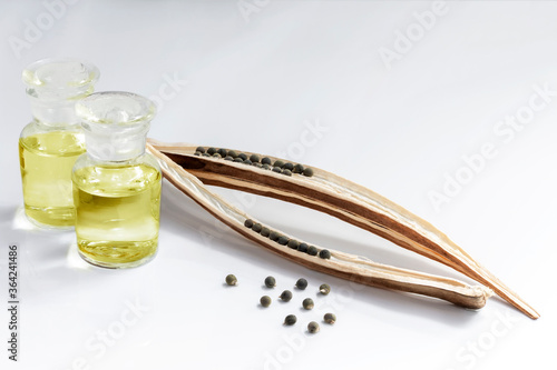 Okra oil in glass bottles and Abelmoschus esculentus seed on a white background, it is help relieve stress and boost sexual performance which is property medicine concept. With copy space for text.