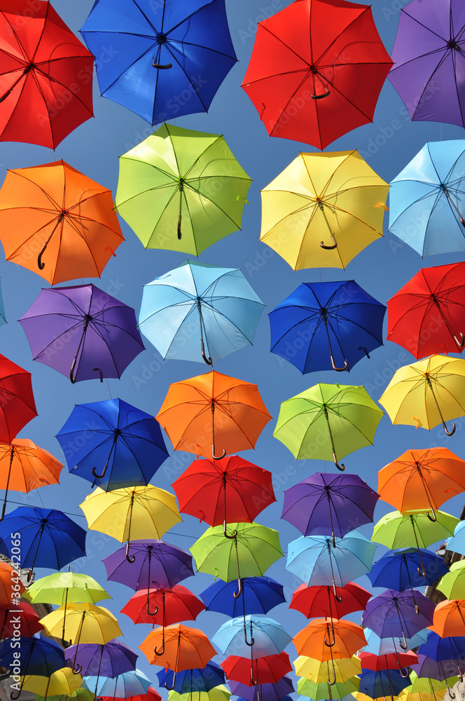 Multicolored umbrellas hang in the sky as a summer installation Multicolored umbrellas hang in the sky as a summer installation