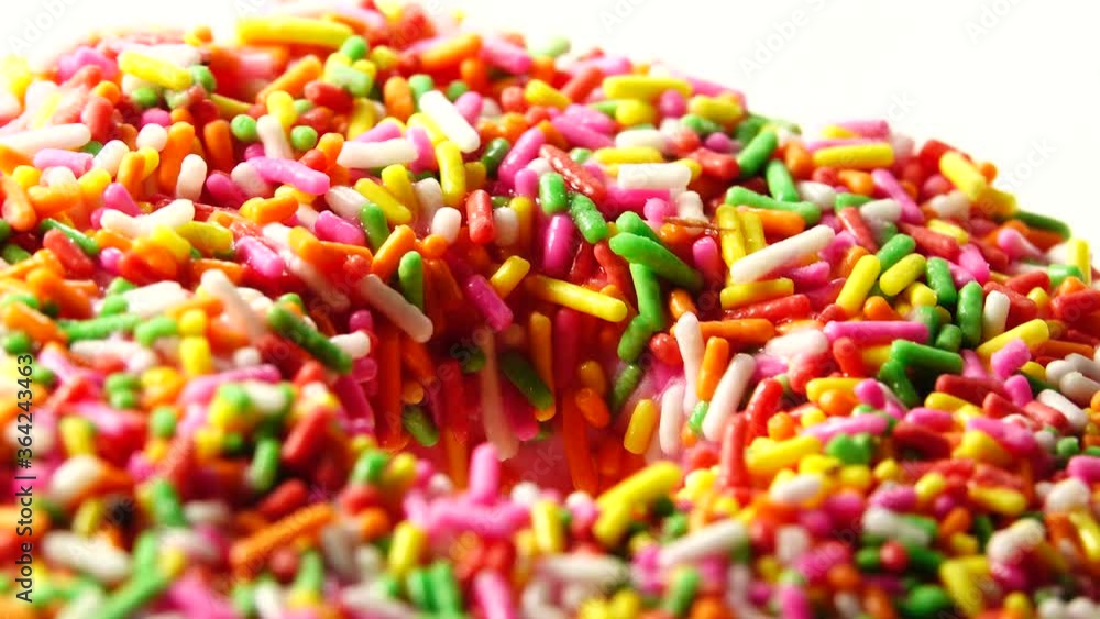 4K Delicious sweet donut rotating on a plate. Top view. Bright and colorful sprinkled donut close-up macro shot spinning on a white background. 4K Delicious sweet donut rotating on a plate. Top view. Bright and colorful sprinkled donut close-up macro shot spinning on a white background.