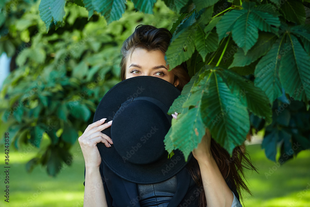 portrait of a beautiful girl in a hat in summer. image of a hipster girl posing in the foliage of a tree