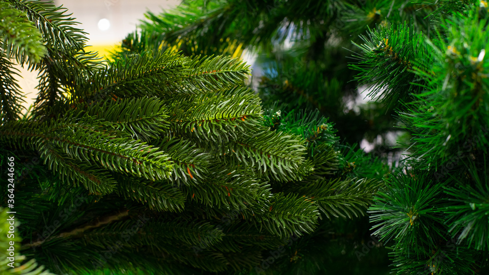 Artificial Christmas tree, green spruce branch with thin plastic needles, close-up background backdrop wallpaper design. Eco-friendly fake New Year spruce green color