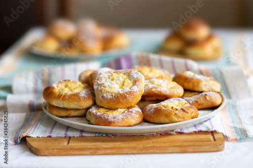 Fragrant mouth-watering buns stuffed with cheese. Homemade dessert on a plate, tablecloth and wooden cutting board. Shallow depth of field