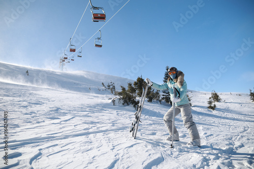 A woman posing with ski in mountain ski resort in winter season,sunny day