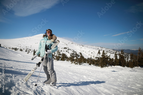 A woman posing with ski in mountain ski resort in winter season,sunny day