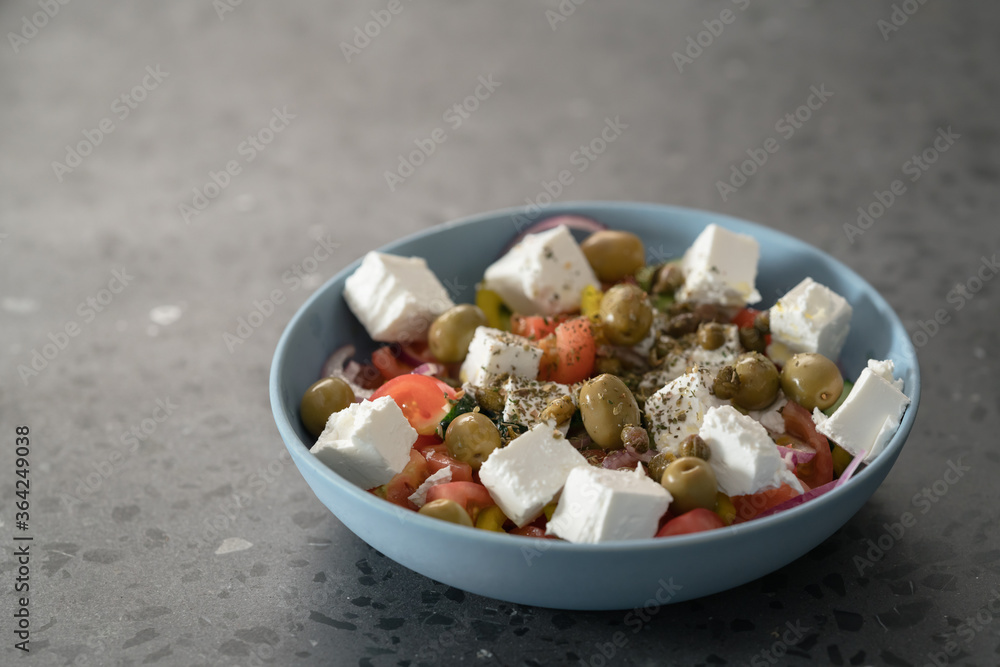 Classic greek salad in blue bowl on concrete countertp with copy space Classic greek salad in blue bowl on concrete countertp with copy space