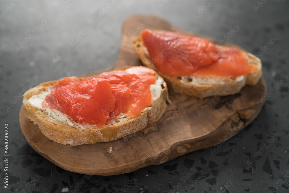 Sandwich with smoked salmon and cream cheese on olive woob board Sandwich with smoked salmon and cream cheese on olive woob board