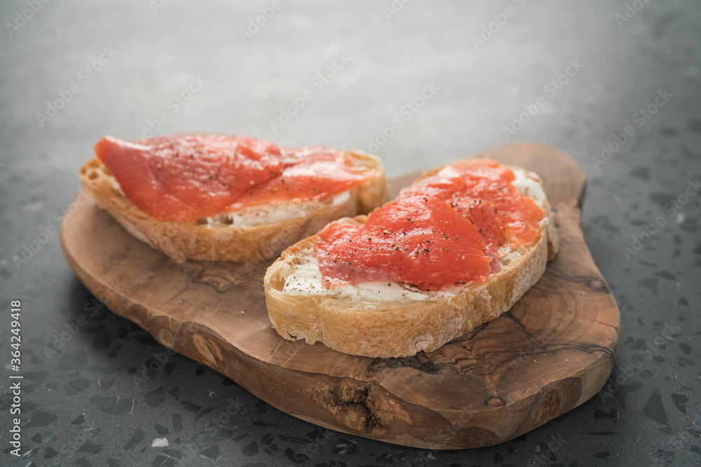 Sandwich with smoked salmon and cream cheese on olive woob board