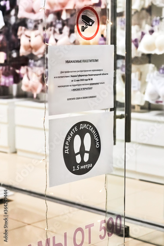 Nizhniy Novgorod - 2020: posters about mandatory mask wearing and safety requirements due to coronavirus outbreak with warning text banner sign in russian at the entrance to the store of the emporium