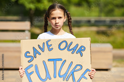 Waist up portrait of cute girl holding sign with SAVE FUTURE writing while protesting for nature and economics outdoors © Seventyfour