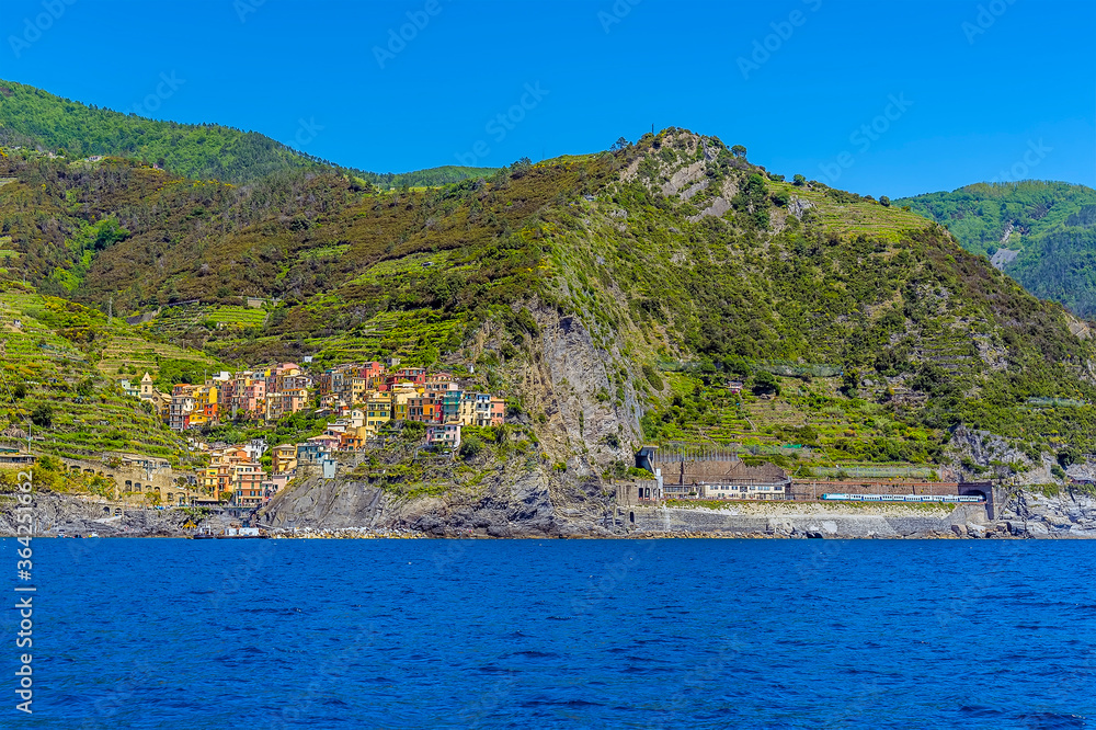 A panorama view from the sea towards the railway station and Cinque Terre village of Manarola, Italy in the summertime
