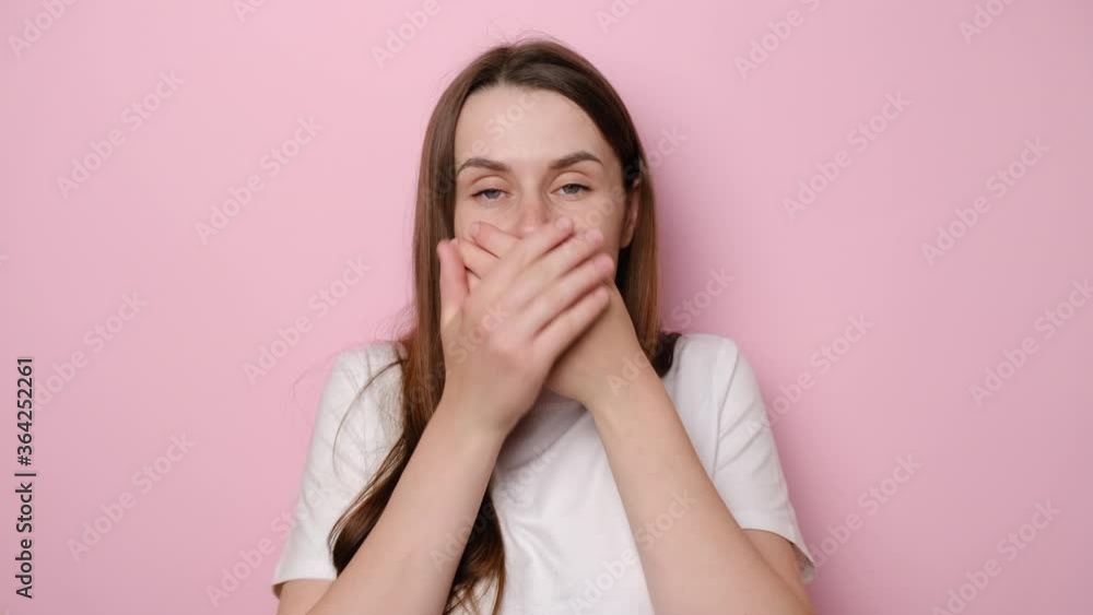Scared young woman looking at camera with big eyes shocked expression, closing mouth zipping lips to keep terrible secret, isolated on pink studio background. People, emotions and unexpectedness Scared young woman looking at camera with big eyes shocked expression, closing mouth zipping lips to keep terrible secret, isolated on pink studio background. People, emotions and unexpectedness