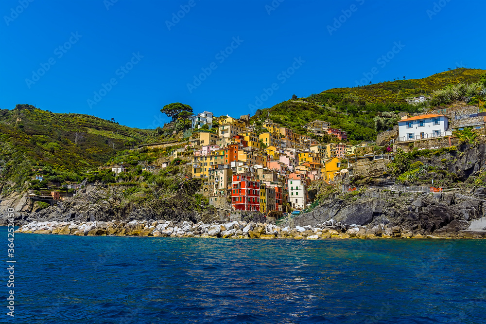 A view from the sea looking back across the harbour breakwater toward the Cinque Terre village of Riomaggiore, Italy in the summertime