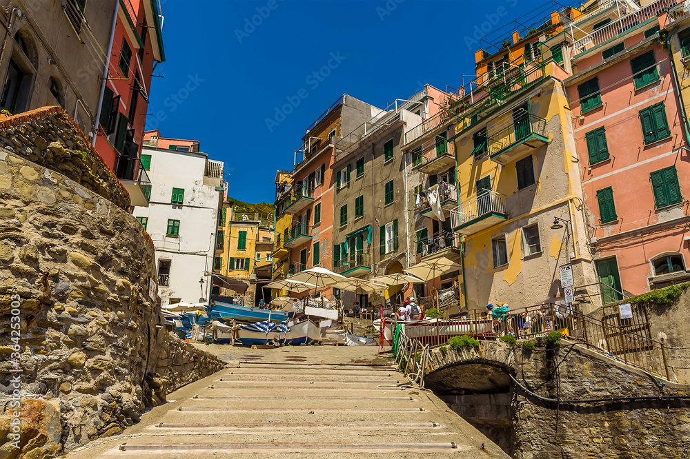 Looking up the slipway towards the tall, colourful houses surrounding the harbour in the Cinque Terre village of Riomaggiore, Italy in the summertime