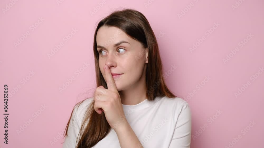 Portrait of worried brunette young woman shushing, asking to keep silence, holding finger on lips to keep mystery, positive girl don't tell secret information, isolated on pink studio background Portrait of worried brunette young woman shushing, asking to keep silence, holding finger on lips to keep mystery, positive girl don't tell secret information, isolated on pink studio background