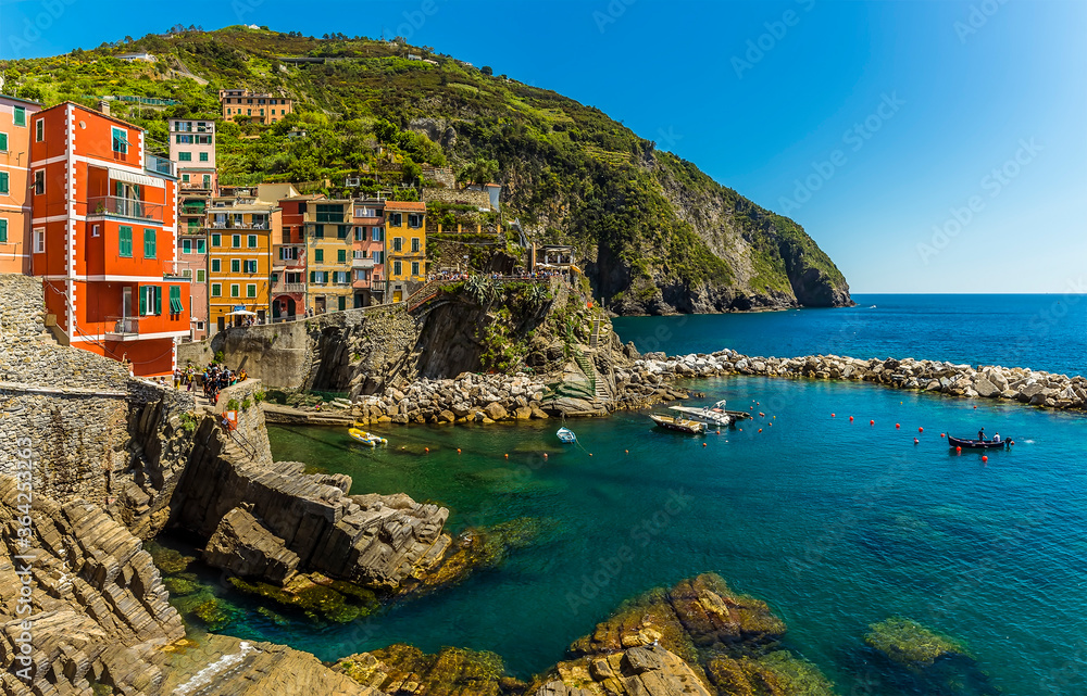 Colourful houses and crystal clear waters in the Cinque Terre village of Riomaggiore, Italy in the summertime