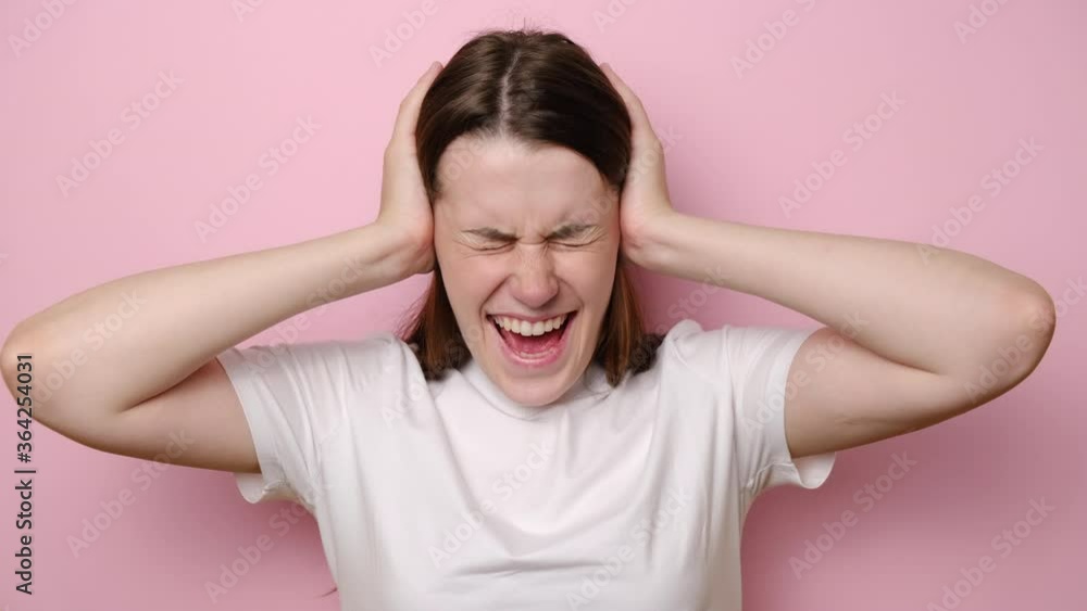 Irritated young woman frustrated loud noise covering ears clasping head, want to stop unpleasant voices in mind. Girl angry with her neighbours who are very noisy, isolated on pink studio background Irritated young woman frustrated loud noise covering ears clasping head, want to stop unpleasant voices in mind. Girl angry with her neighbours who are very noisy, isolated on pink studio background
