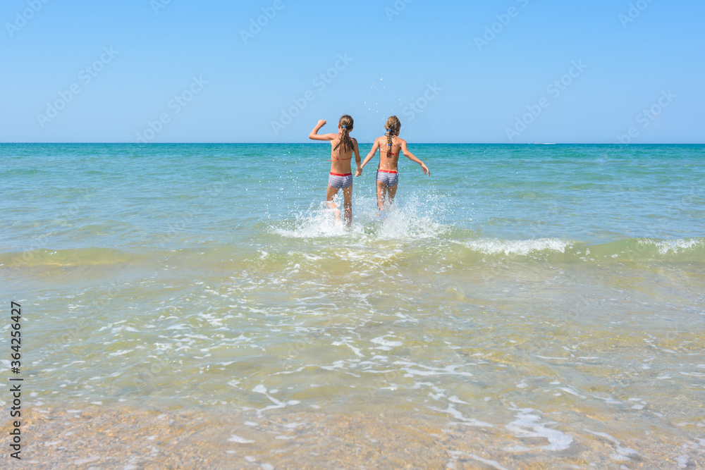 Girls run in the water swimming in shallow water