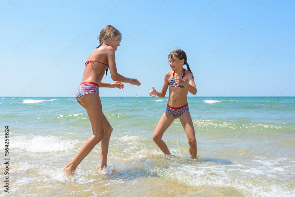 Two girls playing fight on the seashore in the water