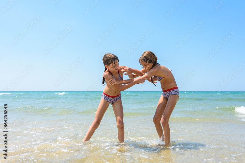 Two girls fight on the sandy beach of the sea