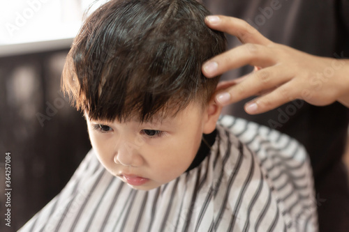 little boy hair with an electric clipper, in barber shop