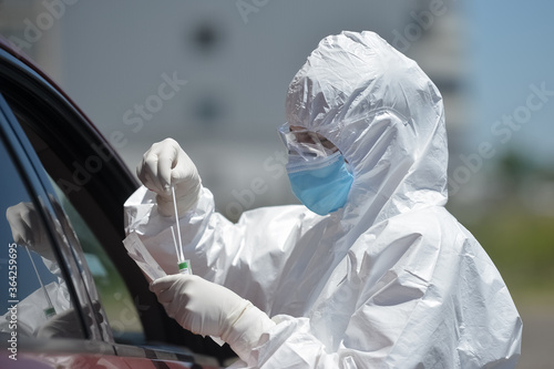 Unrecognizable people wearing protective suit handles a pharyngeal exudate/ swab collection kit for the coronavirus. Test tube for taking OP NP patient specimen sample, PCR DNA testing